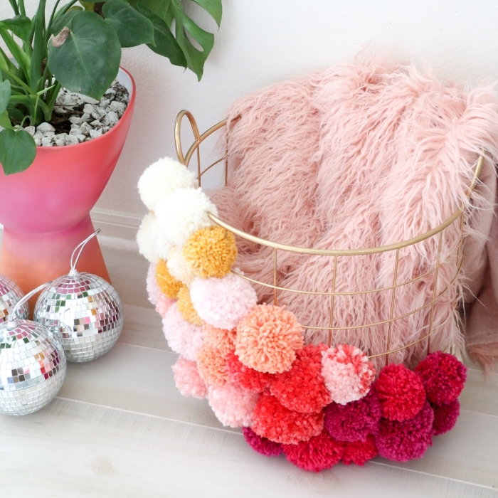 customiser son panier de rangement avec boules de laine de couleurs rouges et pastel, plante verte dans pot à fleur à design ombré