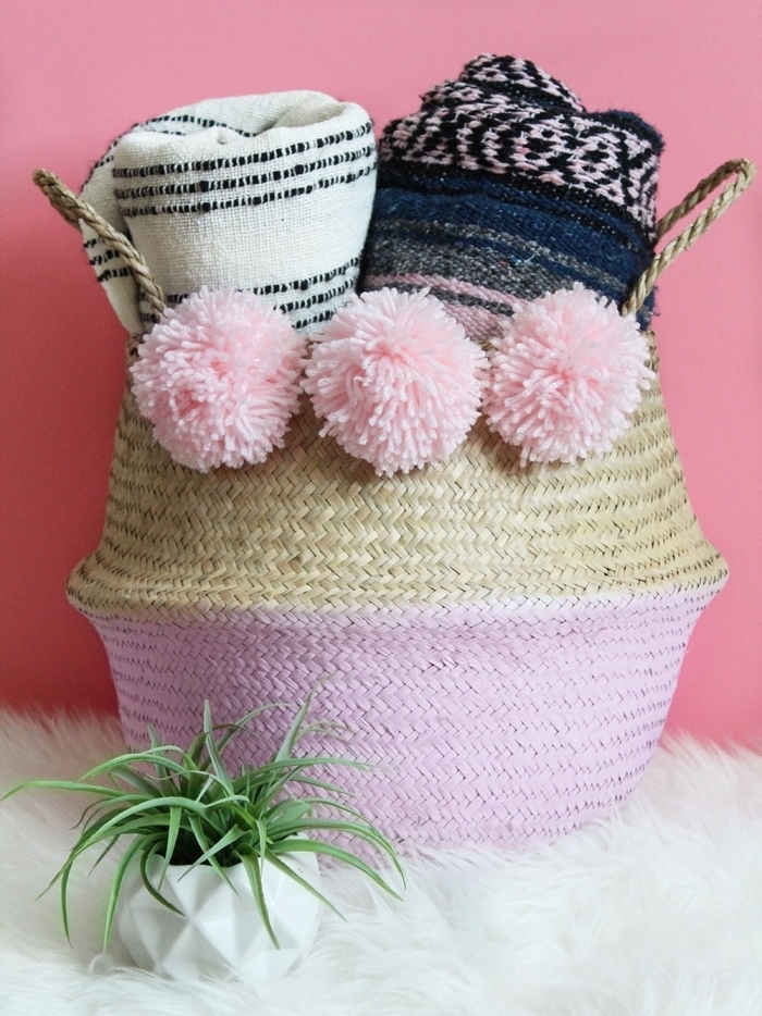 idée comment customiser un panier en paille avec peinture de nuance rose pâle et pompons en laine rose pastel