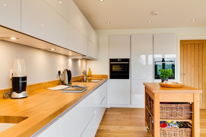 idée décoration moderne dans une cuisine blanche laquée avec meubles sans poignées et plan de travail en bois