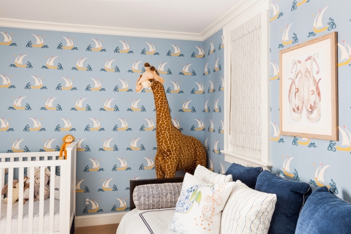 modèle de deco chambre garcon avec papier peint bleu clair à design marine et une peluche grande en forme de girafe