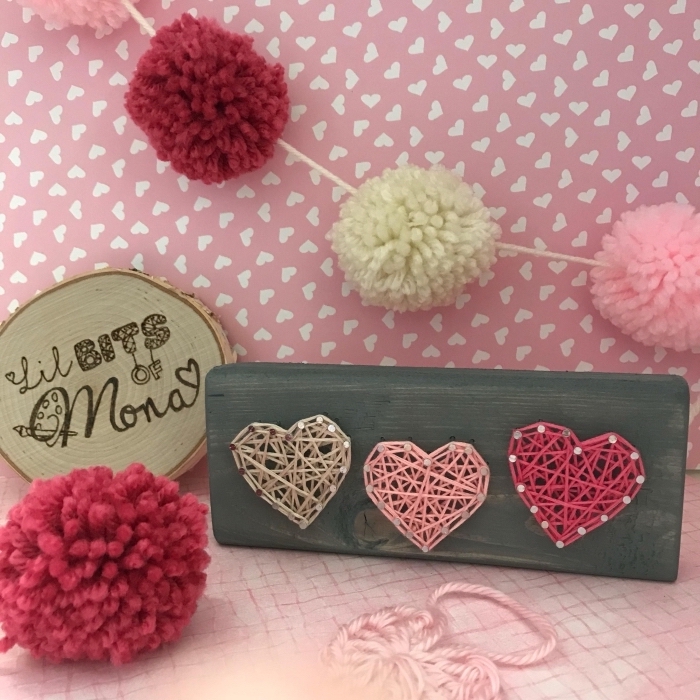 exemple d'accessoires et objets décoratifs dans un coin rose pastel décoré avec guirlande de pompons en laine