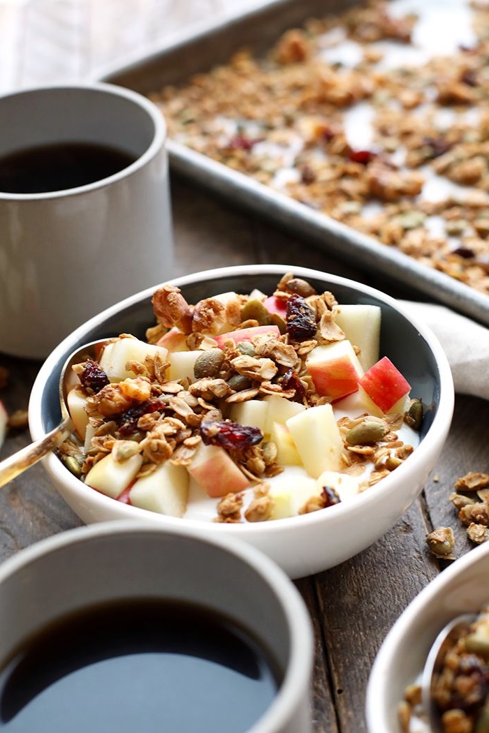 bowl de petit-déjeuner sain de muesli, yaourt grec, pommes, fruits séchés et graines