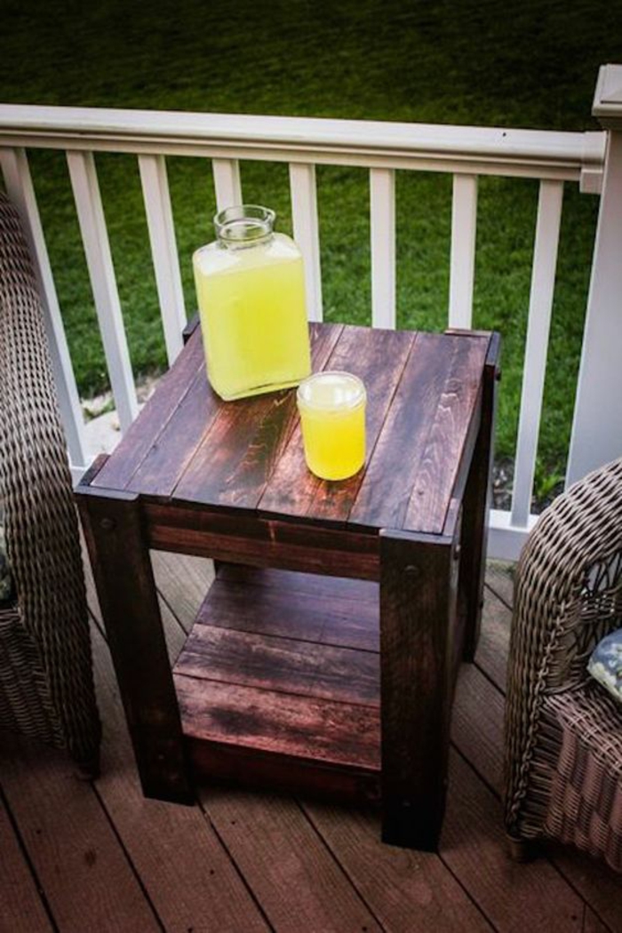table palettes, salon de jardin en palette, table de jardin en palette avec deux niveaux, avec une bouteille en verre avec limonade, verre rempli de limonade 