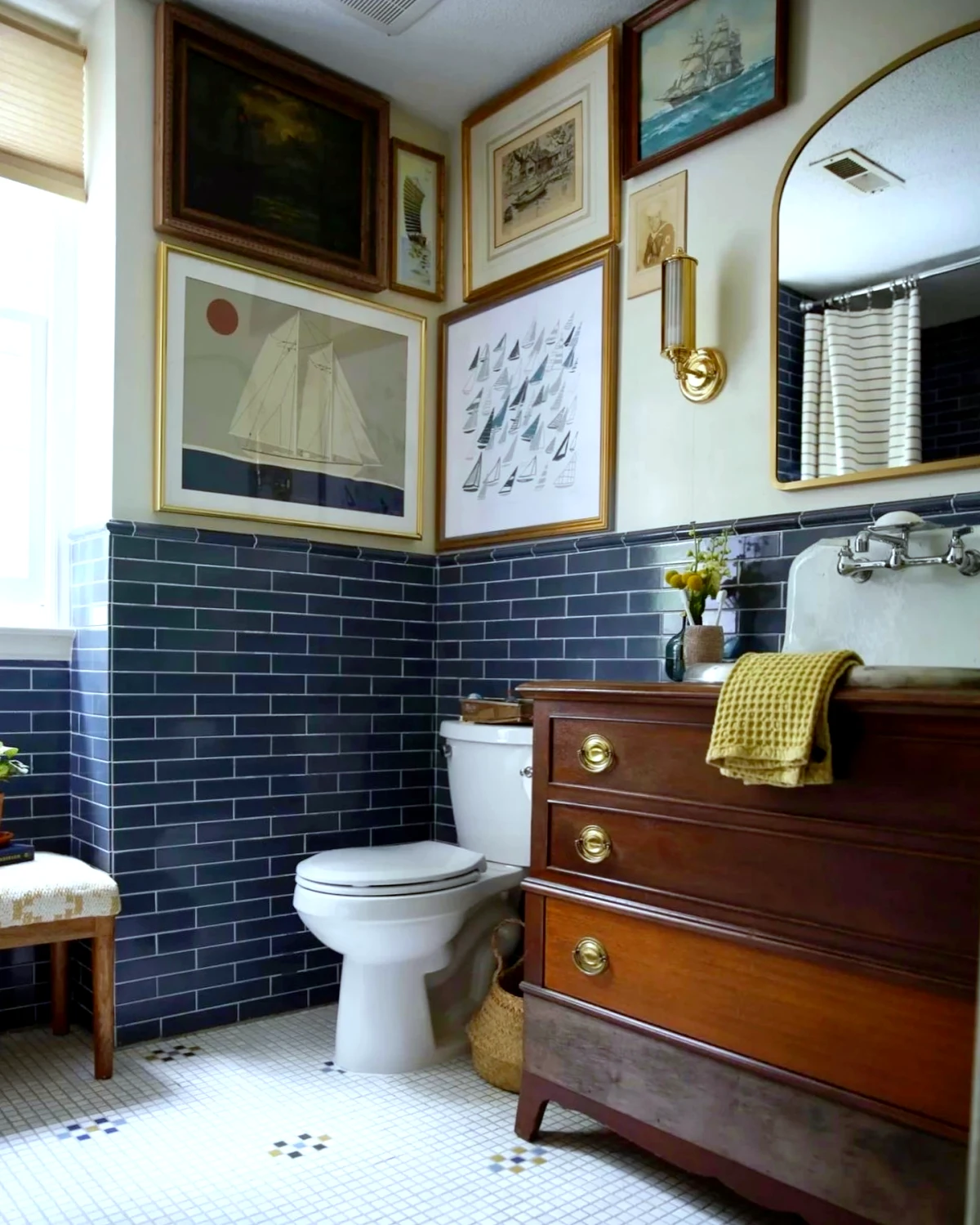 petite salle de baon vintage avec des tableaux au mur et meuble en bois