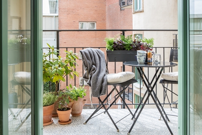 aménagement de balcon avec table ronde et chaises noires, déco de mini jardin urbain avec plantes comestibles