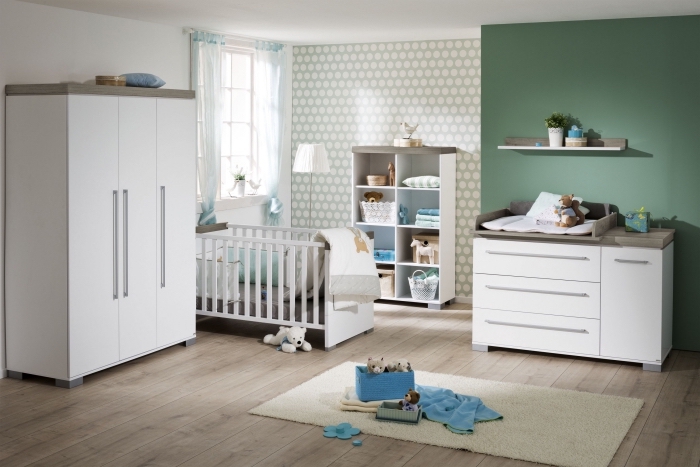 modèle de chambre bébé neutre avec pan de mur vert et papier peint à design géométrique en blanc et vert pâle
