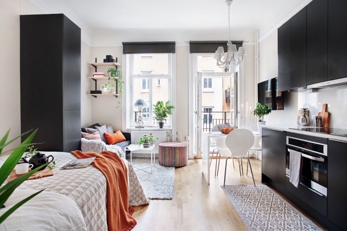 idée déco studio en meubles blanc et noir, ambiance cozy avec un pouf multicolore et coussins et plaid orange