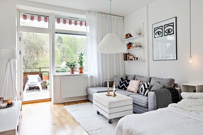 déco cozy dans un petit studio étudiant ou célibataire avec canapé et grand lit, aménagement de balcon avec plantes vertes et chaise cocooning