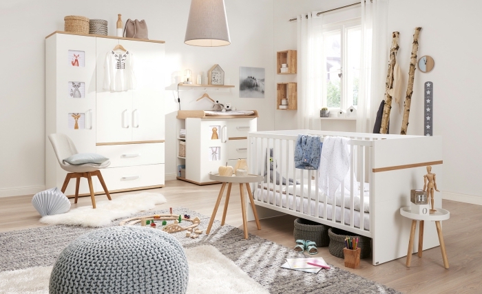 modèle de chambre bebe complete en blanc et bois avec large tapis large moelleux et pouf en crochet de nuance grise