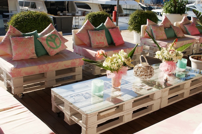coussin salon de jardin palette rose et blanc cassé sur des fauteuils en palettes, table basse palettes avec plateau en verre, deco bouquets de fleurs