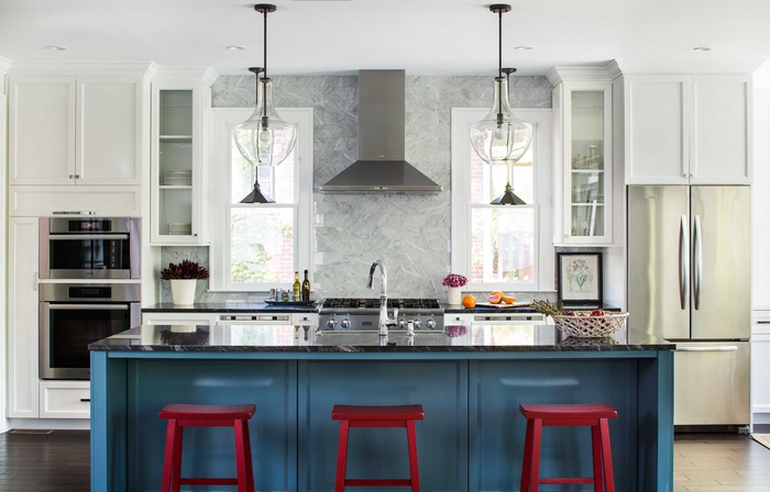 cuisine blanche et grise où le carrelage de la crédence effet marbre se prolonge jusqu'au plafond, cuisine gris et blanc dynamisée par son îlot central rouge et bleu