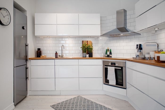 design intérieur contemporain dans une cuisine blanche au plancher de bois clair et crédence blanche à carrelage briques