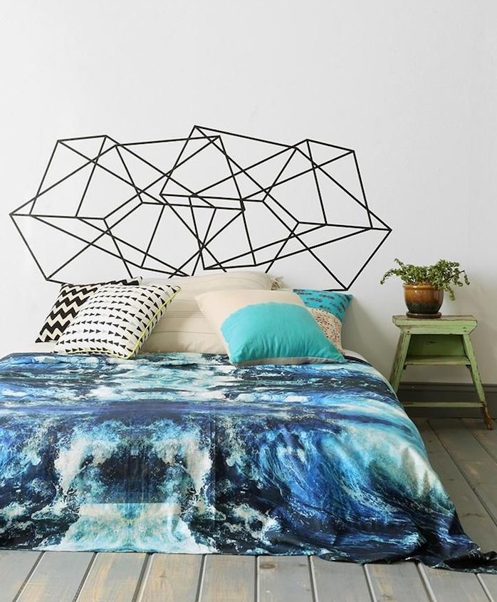 tete de lit originale en motifs geometriques noirs, linge de lit bleu, coussins décoratifs, parquet gris usé, table de nuit vintage