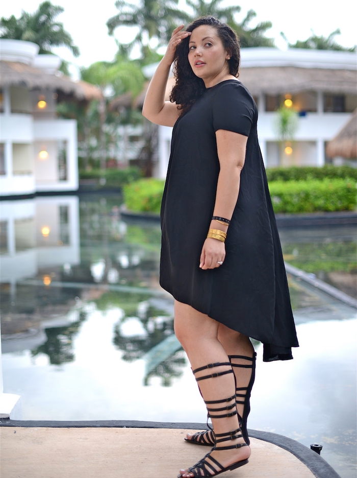 idée de robe pour femme ronde couleur noire et sandales femme noires style grec, cheveux bouclés sur le coté, bracelet or