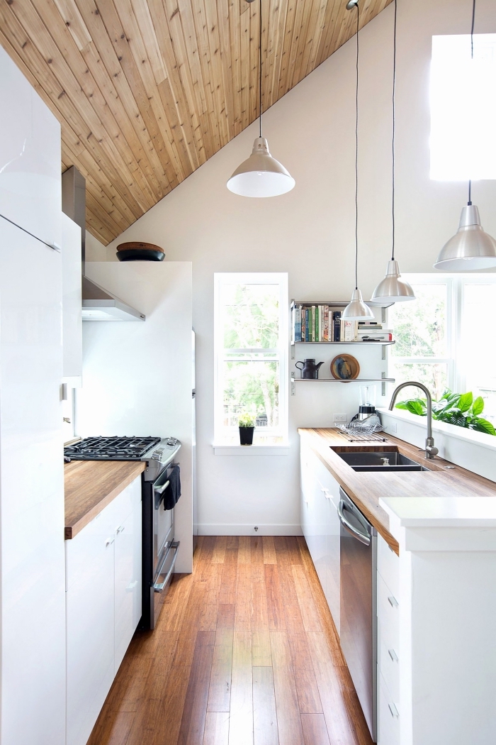 style minimaliste dans une cuisine aux murs blancs avec revêtement de plafond et de plancher en bois et éclairage industriel