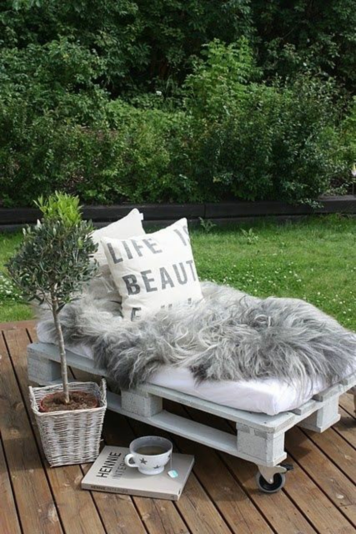 chaise-longue en palettes avec des roues, bois peint en blanc, plante verte-arbrisseau dans un pot marron posé dans une porte-plant en osier tressé peint en blanc , fauteuil palette