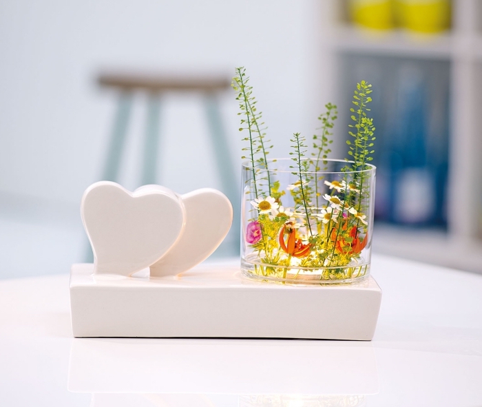 objet de décoration avec support blanc et petits coeurs combinés avec un récipient en verre et plantes vertes