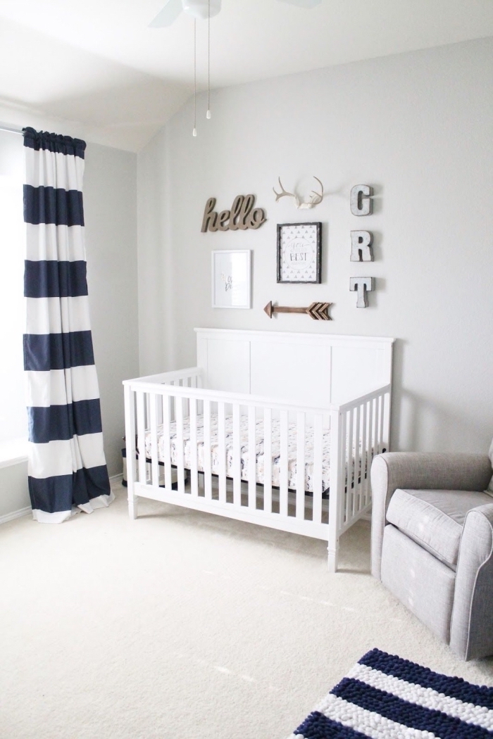 design minimaliste de style marine et boho chic avec rideaux et tapis rayés en bleu marine et blanc et un lit bébé blanc