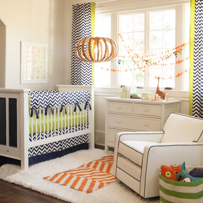 aménagement chambre enfant aux murs beige et plancher de bois foncé avec coussins et rideaux en blanc et bleu marine