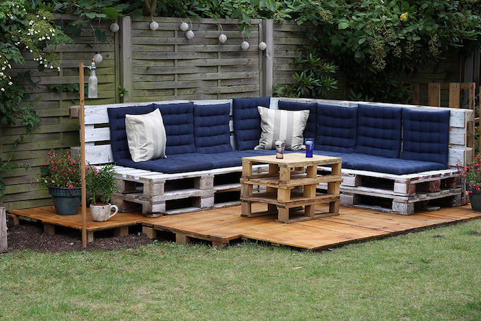 meubles de jardin en palettes avec canapé d angle repeint en blanc et table basse palette sur une terrasse exterieure en bois
