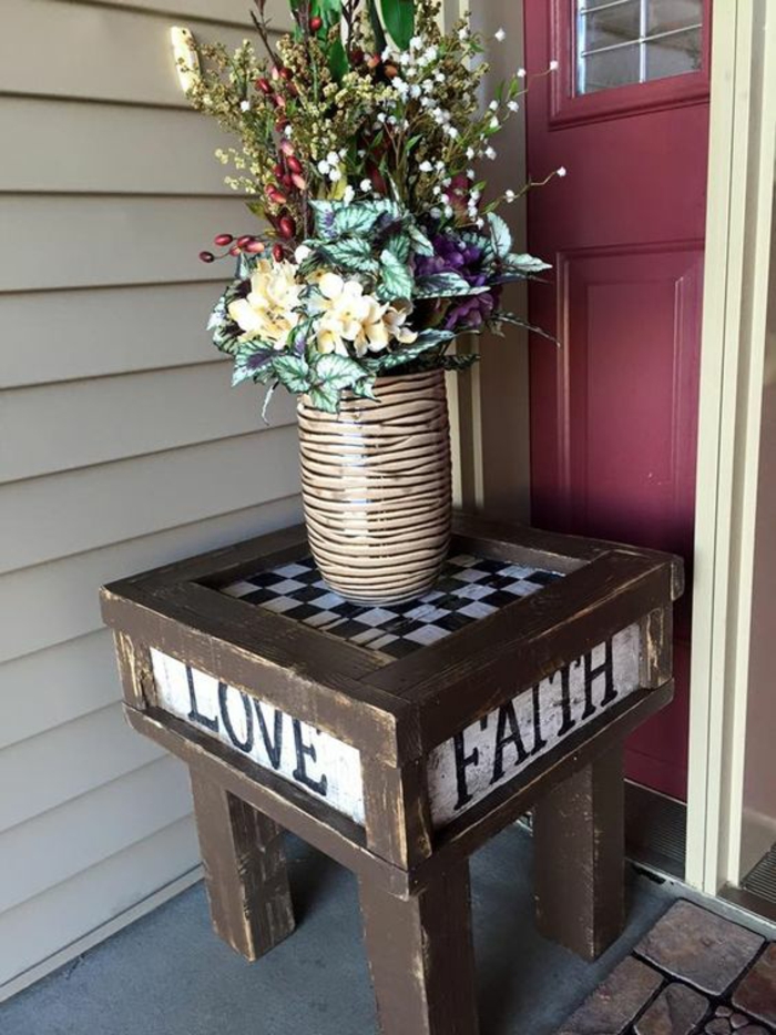 petite table jardin installé devant l'entrée de la maison, meubles de jardin en palettes, vase en rayures félines avec des fleurs de jardin 