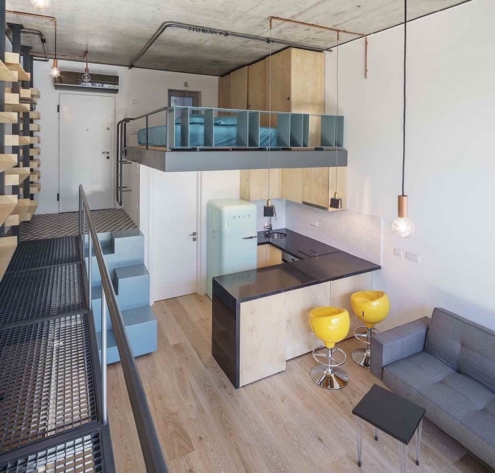 déco de style loft industriel avec plafond à design béton et tuyaux apparents dans un studio étudiant avec petite cuisine d'angle