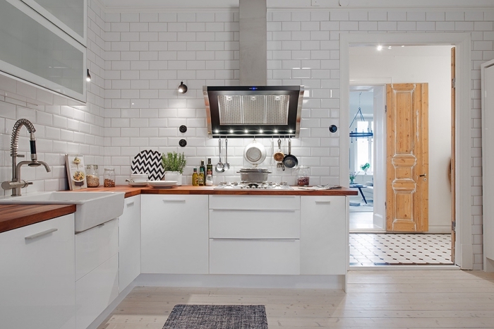 exemple de cuisine blanche avec parquet de bois clair et revêtement mural en carrelage à design briques blanches