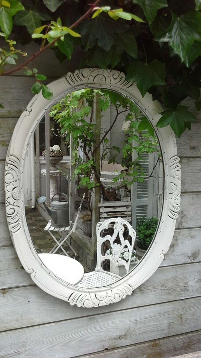 miroir ovale cadre blanc accroché au cintre blanc, meubles de jardin en métal blanc en style baroque, avec des effets de dentelle sur les dossiers, décorer son jardin en style
