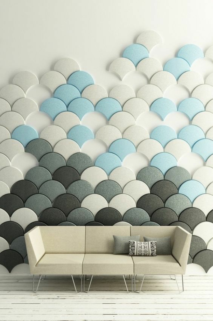 mur décoré avec des mini-panneaux en formes d'écailles de poisson en bleu pastel, gris, blanc et noir, canapé en ivoire aux lignes géométriques minimalistes, decoration murale design, parquet peint en blanc