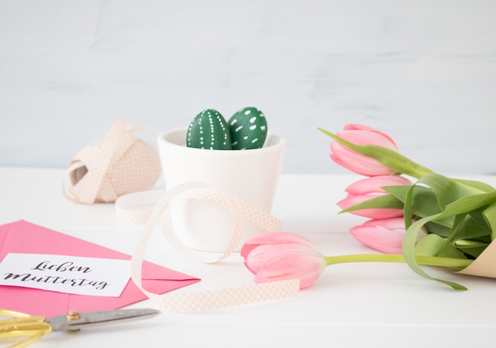 exemple de pot de fleur blanc avec des galets décorés pour imiter des cactus en vert et blanc, activite fete des meres