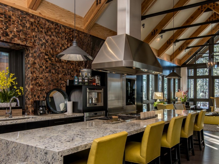 cuisine design loft dans une maison moderne, grande table en granit, lampe industrielle, chaises jaunes