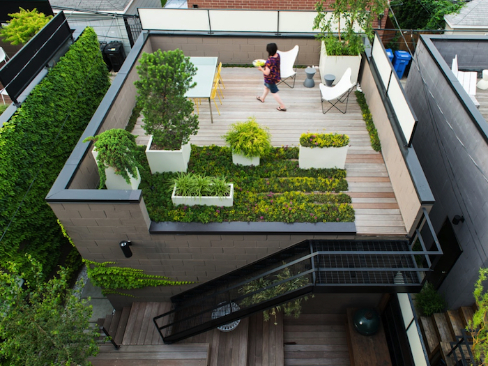 amenagement terrasse exterieure sur le toit d une maison, revetement sol en bois, plantes en bacs, table entourée de chaises