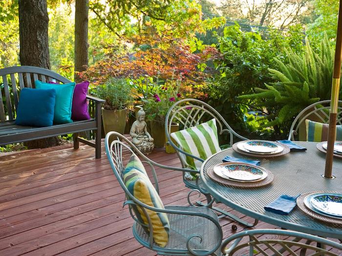 deco terrasse orientale avec coin repas de table et chaises metalliques, revetement sol en composite, banc en bois, statuette bouddha