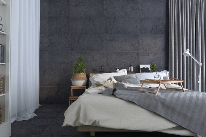 ambiance cozy dans l'esprit scandinave dans une chambre à coucher aux murs gris avec rideaux blancs et meubles en bois