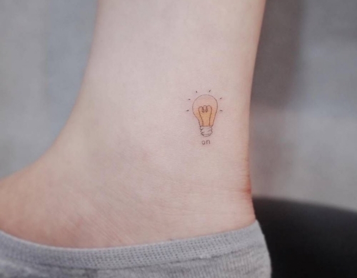 choisir son tatouage symbolique à design minimaliste, modèle de petite ampoule électrique en couleur sur la cheville