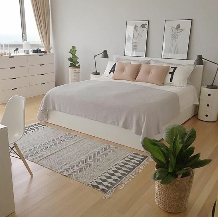chambre à coucher scandinave, carpette ethnique, lit en blanc et gris, sol en lattes de bois, peintures encadrées