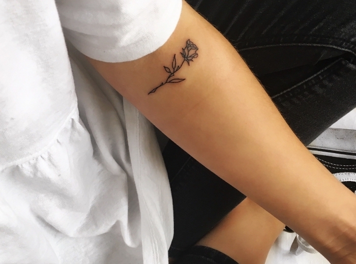 jolie petite rose en encre sur la main féminine, exemple de tatouage doux dans l'esprit minimaliste pour femme