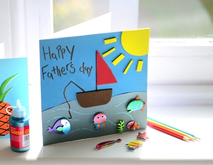 idée comment faire une carte fête des pères maternelle, avec fond bleu paysage marin avec bateau, soleil et animaux de mer en feutrine