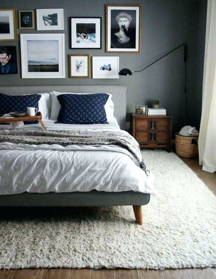 tapis blanc dans une chambre grise, cadres photos, chevet en bois, panier rustique, lampe de sol
