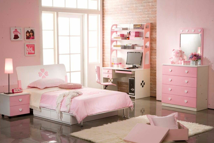 chambre fille ado en rose et blanc, murs roses, meubles roses avec des poignées en forme de cœurs blancs, tapis rectangulaire au poil long, bureau en blanc et en couleur pêche 
