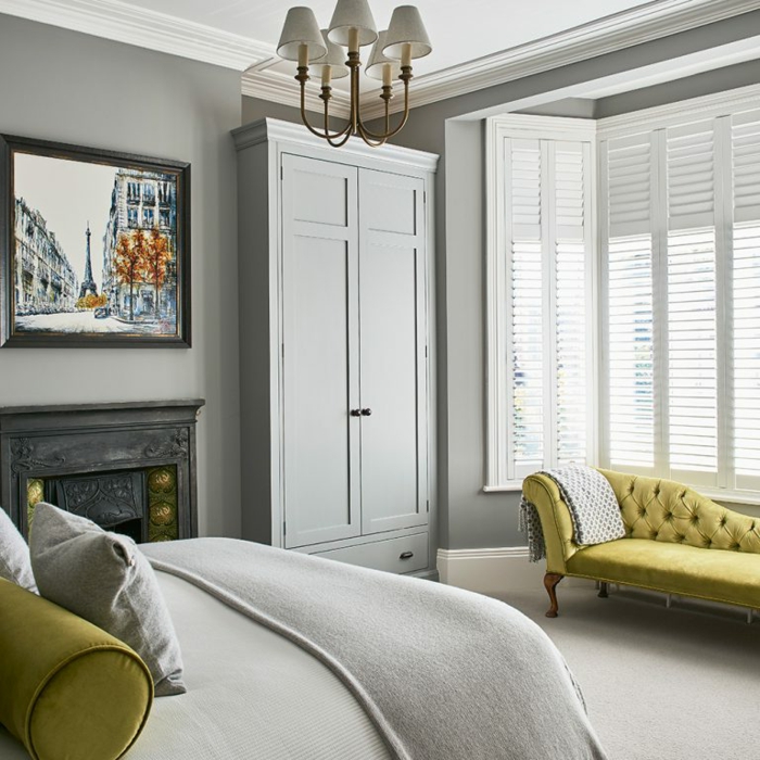 sofa baroque en couleur moutarde dans une chambre à coucher adulte moderne, plafonnier baroque, armoire grise, peinture de la tour eiffel