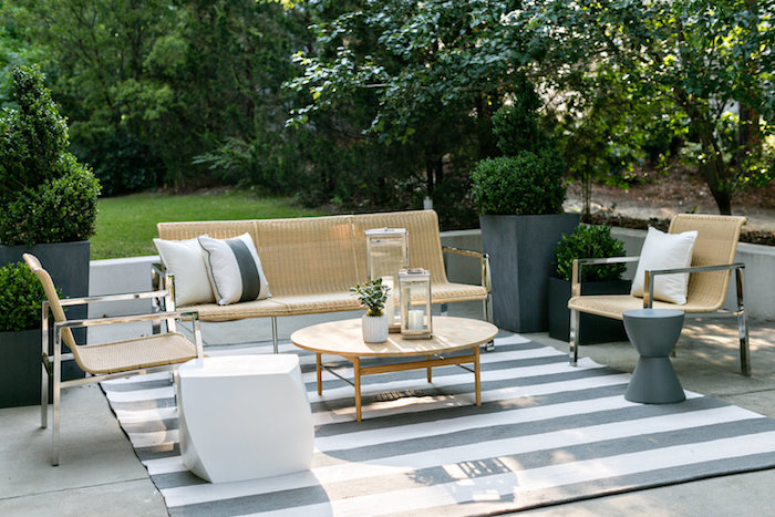 deco terrasse avec revetement en beton, table basse bois, tapis gris et blanc, canapé et chaises rotin et metal, buis en bacs à fleurs