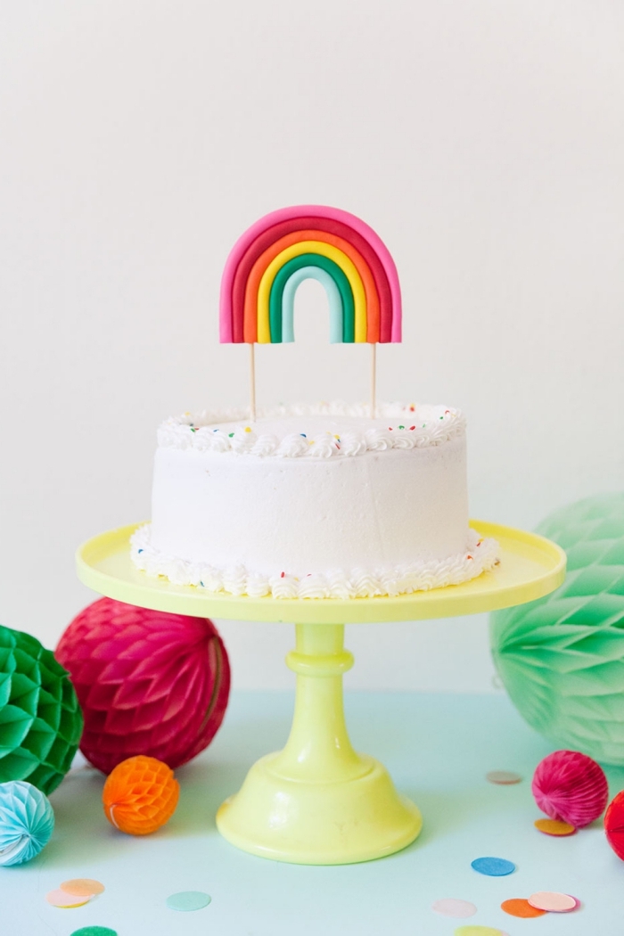 jolie décoration de gâteau arc en ciel au glaçage beurre avec un cake topper arc-en-ciel modelé en pâte à sucre