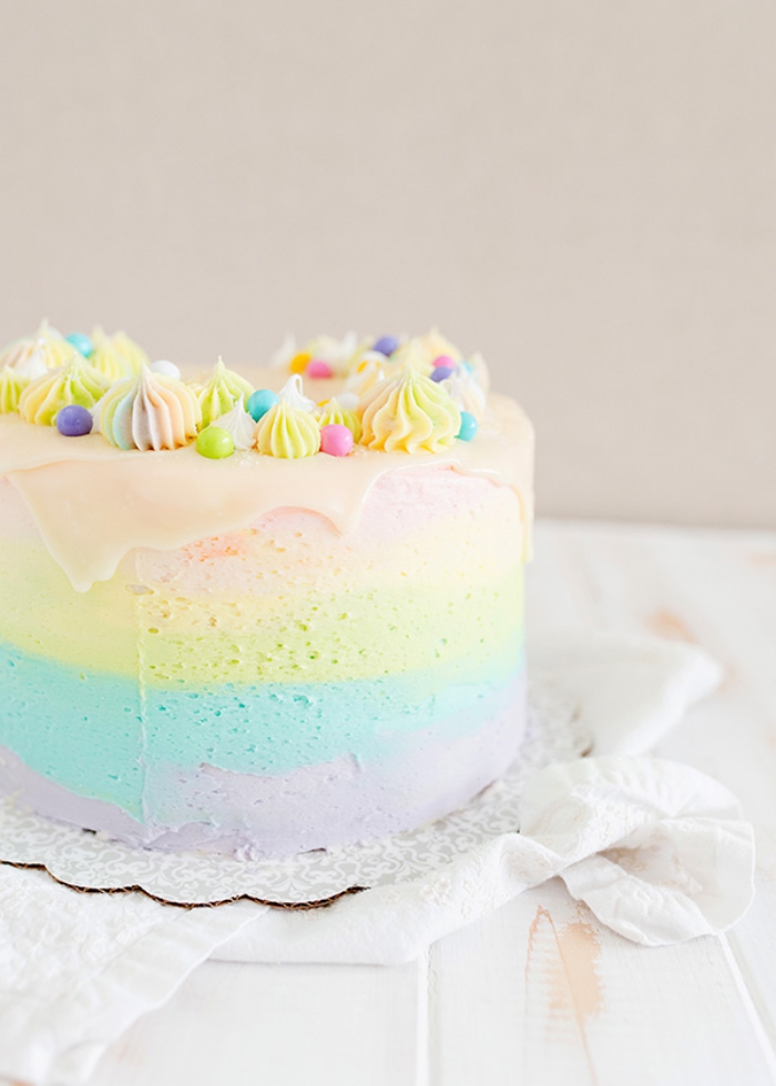 recette de rainbow cake tout en douceur à plusieurs couches en nuances pastel et au glaçage coulant de chocolat blanc