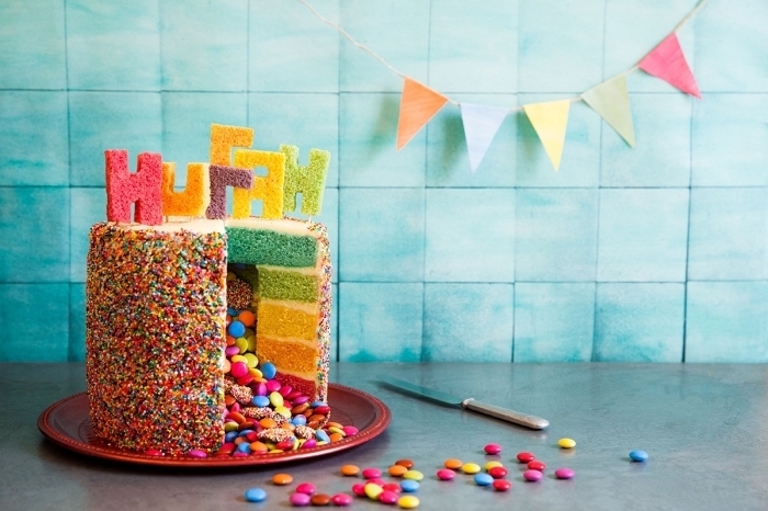 recette de gateau au smarties façon piñata cake décoré avec des vermicelles colorées et des lettres découpées dans les génoises colorées