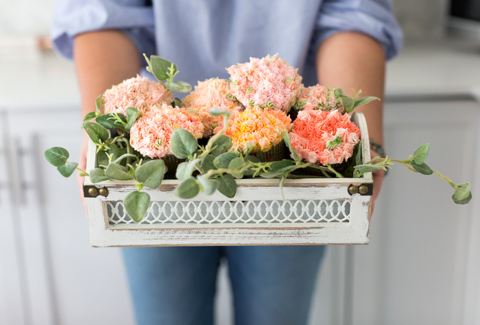 une jolie composition florale hors du commun réalisée avec des cupcakes en forme de fleurs dans un panier vintage, activite fete des meres pour réaliser un cadeau gourmand