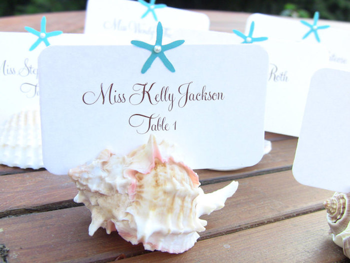 exemple de deco de table mariage bord de mer avec coquille de mer et une étiquette blanche inséré, déco étoile bleue