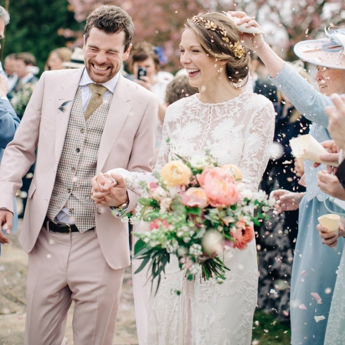 un costume marié de trois pièces en nuance très douce du rose pastel assorti avec des accessoires dans les tons beige et marron