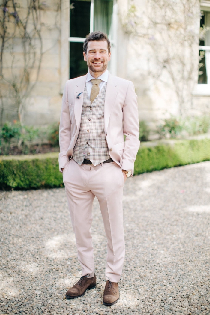 un costume marié de trois pièces en nuance très douce du rose pastel assorti avec des accessoires dans les tons beige et marron