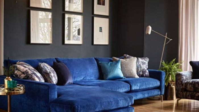 grand canapé bleu, coussins déco, petite table en matière argentée, peinture murale sombre
